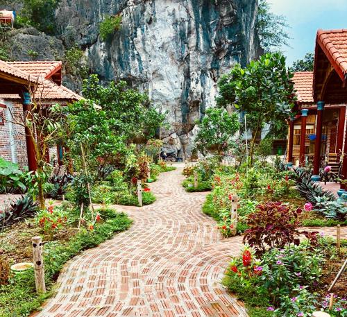 a brick path with flowers and a mountain in the background at Ruby Homestay in Ninh Binh
