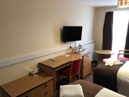 Habitación de hotel con escritorio, TV y cama en The Brae Hotel en Brae