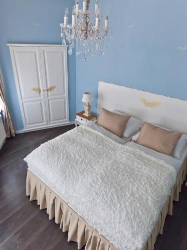 a bedroom with a large white bed with a chandelier at Cathedral Prague Apartments in Prague