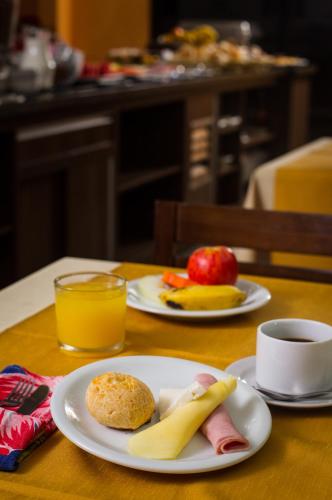 two plates of food on a table with fruit and orange juice at LEON PARK HOTEL e CONVENÇÕES - Melhor Custo Benefício in Campinas