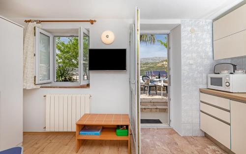 a kitchen with a table and a tv on a wall at Villa Jolanda Apartments in Dubrovnik