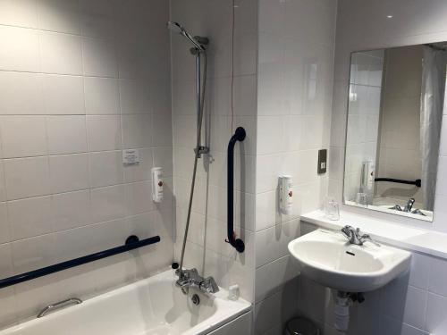 a bathroom with a sink, mirror, and bathtub at Ramada Milton Keynes in Milton Keynes