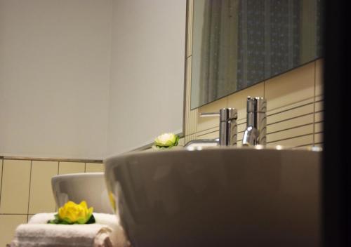 un lavandino in bagno con due fiori sopra di A casa di Tony Sicilian Holidays Black a Sciacca