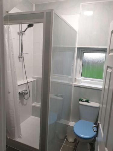 a bathroom with a shower and a toilet with a blue seat at Browning House Bedrooms I Long or Short Stay I Special Rate Available in Derby