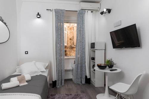 Kleines weißes Zimmer mit einem Bett und einem TV. in der Unterkunft Guest House Tomasi One in Dubrovnik