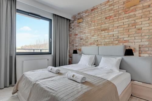 格地尼亞的住宿－The Scandic Suite Sopot-Gdynia Apartment，一间带砖墙和大床的卧室