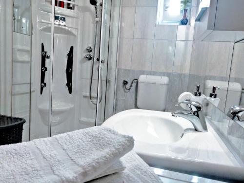 a white bathroom with a sink and a shower at Adria Apartments and Rooms in Dubrovnik