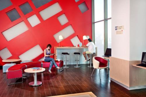 a woman sitting on a couch in a room with a red wall at Ibis Cancun Centro in Cancún