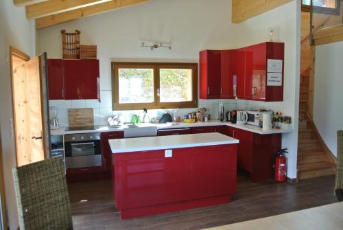 uma cozinha com armários vermelhos e um balcão branco em La Tzoum'hostel em La Tzoumaz