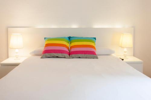 a white bed with a colorful pillow on it at Ramblas Apartments in Barcelona