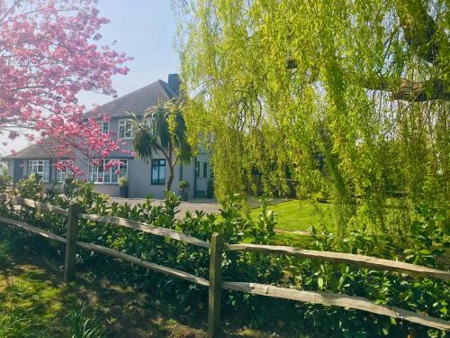 a fence in front of a house with a tree at Bell Lodge in Chichester