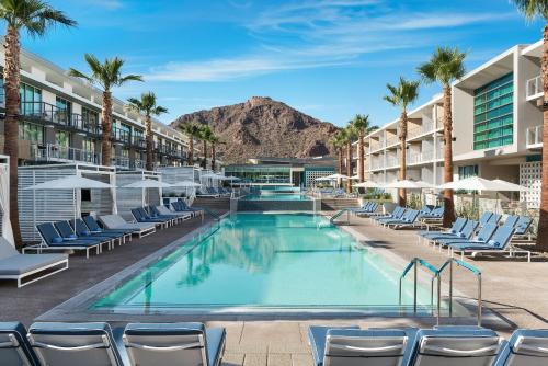 a beach with a pool, chairs, and tables at Mountain Shadows Resort Scottsdale in Scottsdale