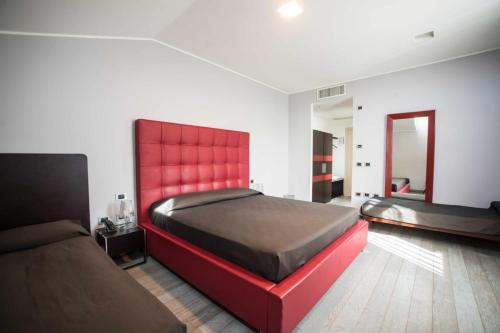 una camera con 2 letti e una testiera rossa di Blue Hotel a Suzzara