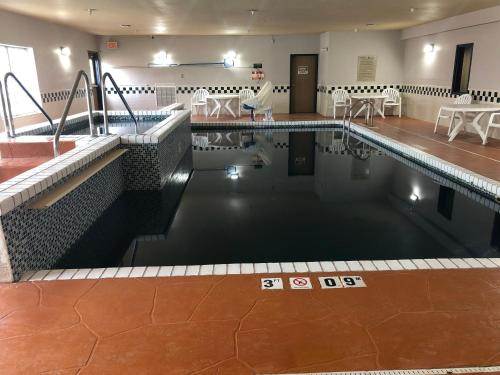a swimming pool with tables and chairs in a building at Country Inn & Suites by Radisson, Topeka West, KS in Topeka