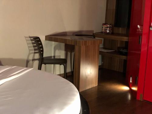 a room with a desk and a table and a bed at Snob Motel (Adult Only) in Belo Horizonte
