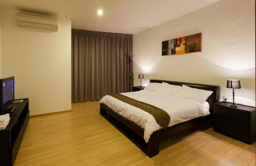 a hotel room with a bed and a television at Luxfort 118 Service Suites in George Town