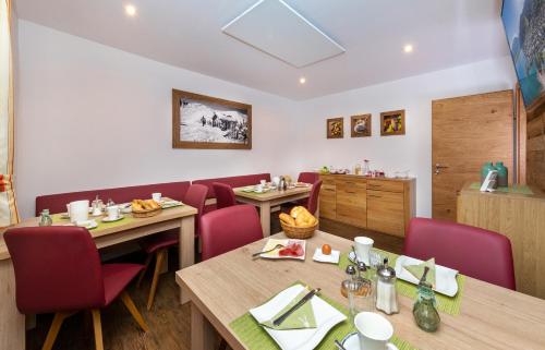 a restaurant with wooden tables and red chairs at Appartement Pension Albert summercard and free parking included in Zell am See