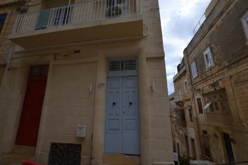 a building with a blue door and a balcony at The Penthouse Flat-terrace&view in Senglea