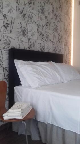 a bed with white sheets and a chair in a room at Casa Lidia - ALLOGGI SMART in Breganze
