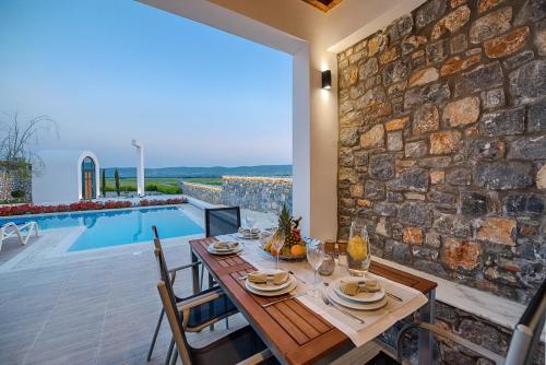 a dining room with a table and a stone wall at Prasonisi Villas in Kattavía