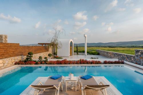 een villa met een zwembad met stoelen en een tafel bij Prasonisi Villas in Kattavía