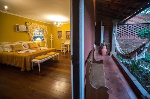 a bedroom with yellow walls and a bed in a room at Pousada Quinta dos Pássaros Itaipava in Itaipava