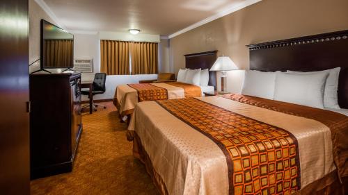 a hotel room with two beds and a desk at Lompoc Valley Inn and Suites in Lompoc