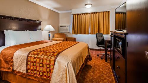 a hotel room with a large bed and a chair at Lompoc Valley Inn and Suites in Lompoc