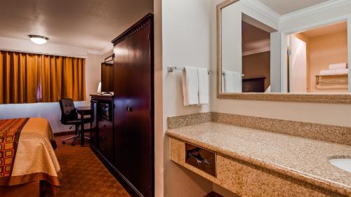 a hotel room with a bathroom with a bed and a sink at Lompoc Valley Inn and Suites in Lompoc