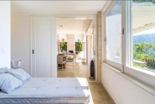 Un dormitorio con una cama y una ventana grande. en Paraiso Romântico Inesquecível Praia Vermelha do Sul Ubatuba, en Ubatuba