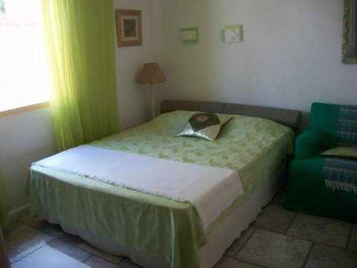 um pequeno quarto com uma cama e uma cadeira verde em Casa Caiçara no Caborê em Paraty