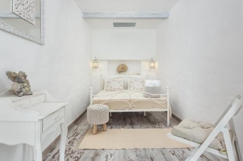 a white bedroom with a bed and a chair at CASA DO PESCADOR by Ammonite&Co in Olhão