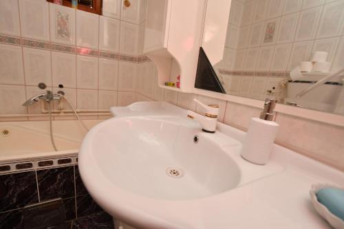 La salle de bains est pourvue d'un lavabo blanc et d'une baignoire. dans l'établissement Villa Nena, à Kladovo