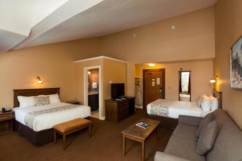 a hotel room with two beds and a couch at Irwin's Mountain Inn in Banff
