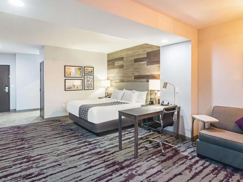 a hotel room with a bed and a desk and a couch at La Quinta by Wyndham Dallas - Wylie in Wylie