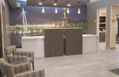 a lobby with chairs and a bar with a painting on the wall at La Quinta by Wyndham Wichita Airport in Wichita