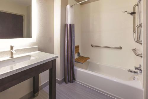 a bathroom with a tub and a sink and a shower at La Quinta by Wyndham Terre Haute in Terre Haute