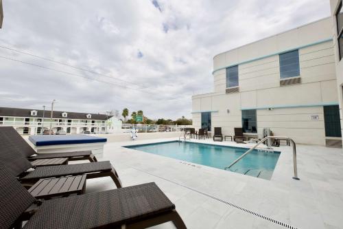 une piscine avec des chaises et un bâtiment dans l'établissement voco St Augustine Historic Area, an IHG Hotel, à Saint Augustine