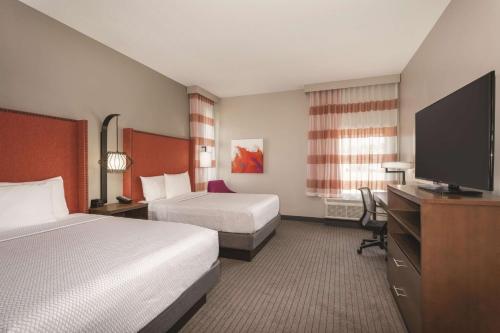a hotel room with two beds and a flat screen tv at La Quinta by Wyndham South Jordan in South Jordan