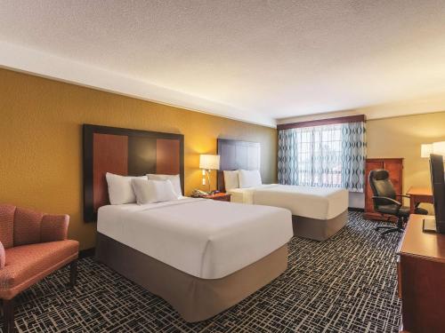 a hotel room with two beds and a chair at La Quinta by Wyndham Deming in Deming