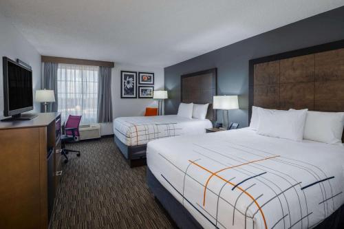 a hotel room with two beds and a flat screen tv at La Quinta by Wyndham Atlanta Douglasville in Douglasville