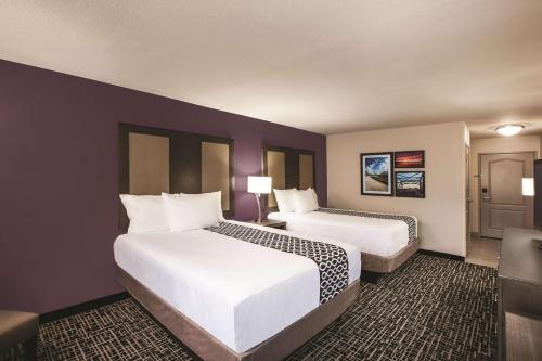 two beds in a hotel room with purple walls at La Quinta by Wyndham Walker - Denham Springs in Walker