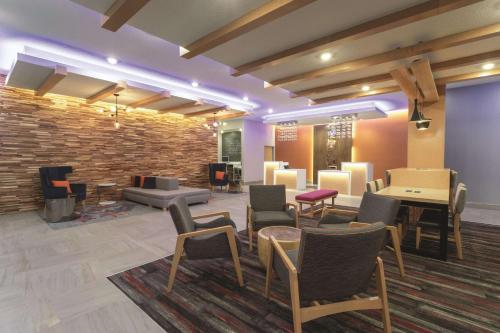 a lobby with chairs and tables and a brick wall at La Quinta by Wyndham South Jordan in South Jordan