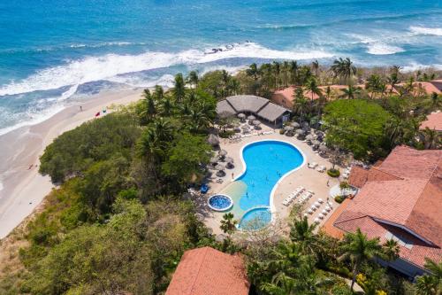 einen Luftblick auf ein Resort mit Pool und Strand in der Unterkunft Occidental Tamarindo - All Inclusive in Tamarindo