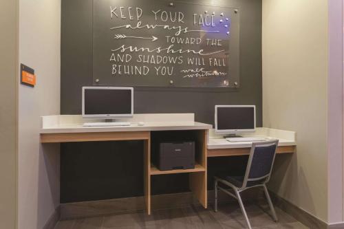 a desk with two computer monitors and a chair at La Quinta by Wyndham South Jordan in South Jordan