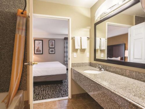 a bathroom with a bed and a sink and a mirror at La Quinta by Wyndham Deming in Deming