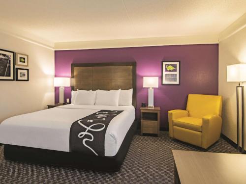 a hotel room with a large bed and a yellow chair at La Quinta by Wyndham Oklahoma City Norman in Norman