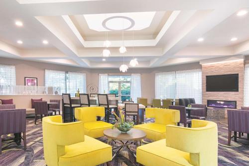 a large waiting room with yellow chairs and tables at La Quinta by Wyndham Atlanta Conyers in Conyers