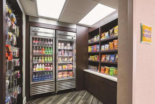 a grocery store aisle with refrigerators and drinks at La Quinta by Wyndham Dallas Plano West in Plano