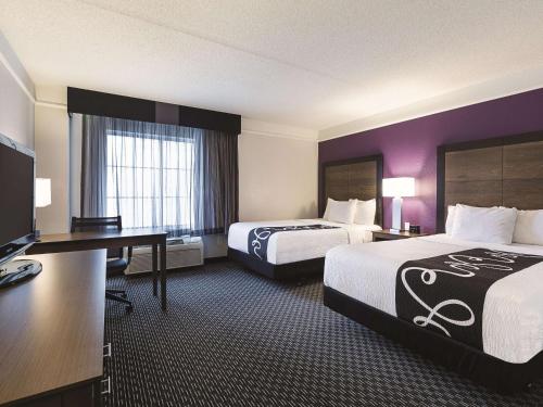 a hotel room with two beds and a desk at La Quinta by Wyndham Dallas Plano West in Plano